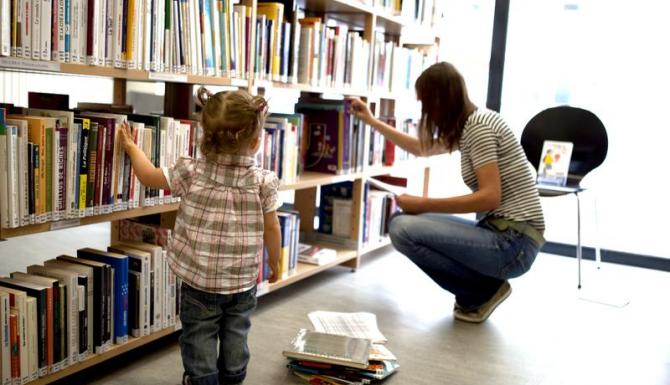 rayonnages, une petite fille fouille dans les libres
