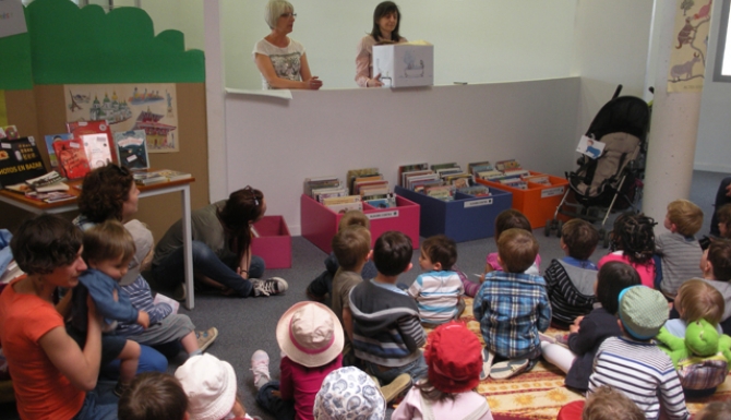 Animation autour de contes : public jeune rassemblé autour de deux bibliothécaires