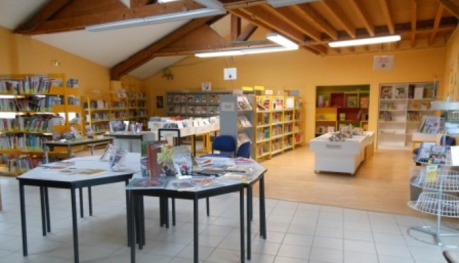 espaces de la bibliothèque. Grande salle haute sous plafond, tables de présentation en premier plan