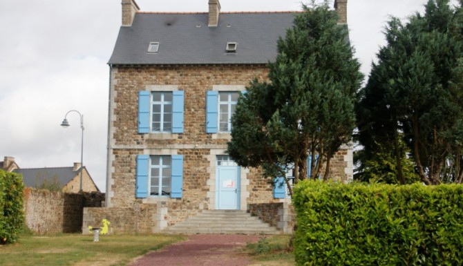 vue de l'extérieur de la bibliothèque. Petite maisonnette aux volets bleus