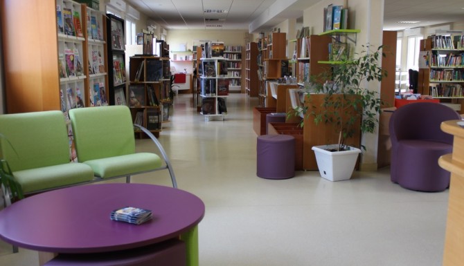 Espaces de la médiathèque. fauteuils verts et tables basses violettes
