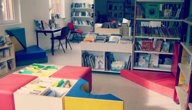 Fonds de la bibliothèque, on y voit des rayonnages, une table de travail et la banque de prêt