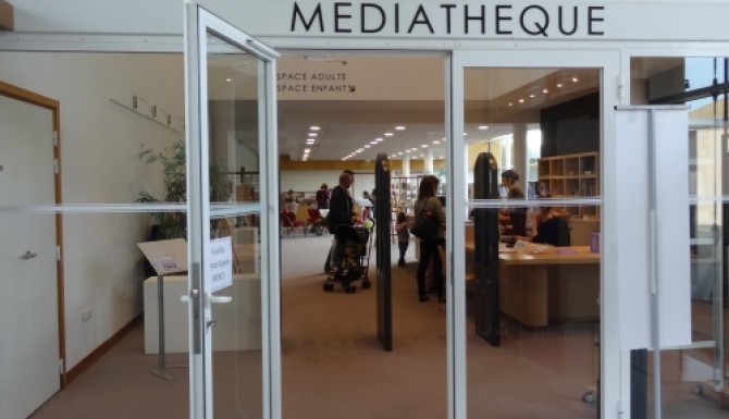 entrée de la médiathèque. porte vitrée séparant le hall du centre culturel de la médiathèque à droite de l'entrée.