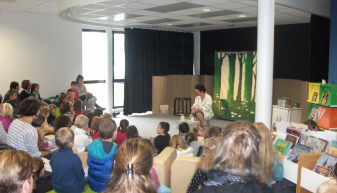 heure du conte. Enfants et parents en arc de cercle autour de la conteuse