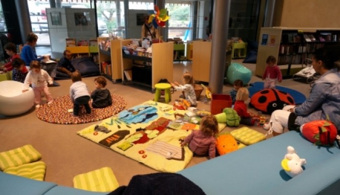 Espace des tout-petits avec des tapis de couleur et des bacs d'albums