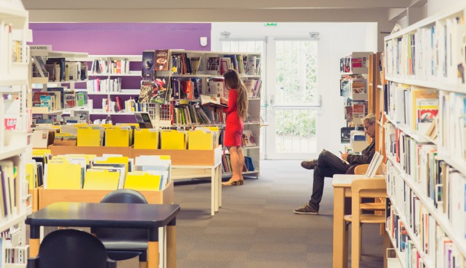 espaces de la bibliothèque. Mur du fonds violet, des bacs, des fauteuils, des tables et des rayonnages