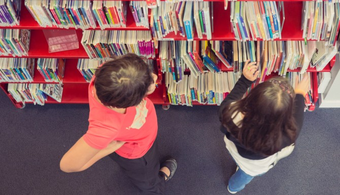 espaces vu du dessus, des personnes cherchent des livres dans une étagère rouge