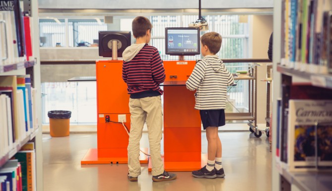 enfants utilisant les automates de prêt oranges