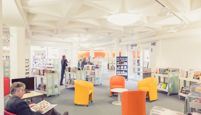 espaces où l'on peut voir, des usagers, des bacs, des fauteuils de couleurs, un automate de prêt et un catalogue consultable