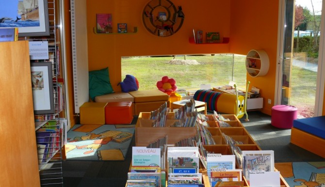 espace des enfants très coloré. Murs oranges, belle baie vitrée basse, tapis et bacs de couleur