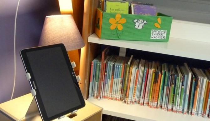tablette numérique en libre accès en jeunesse. Ena rrière-plan on distingue des livres