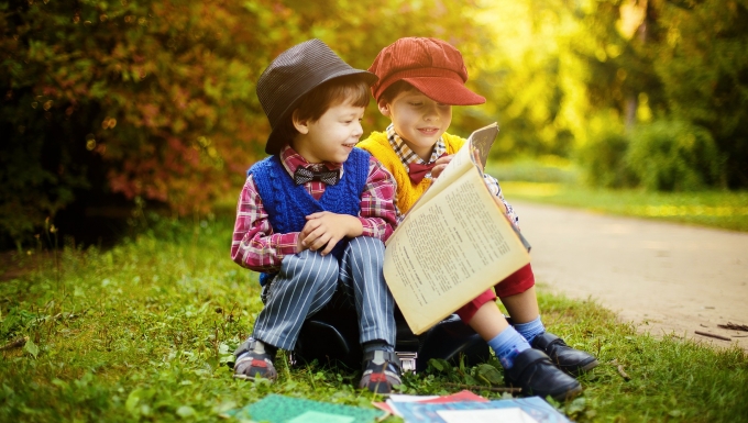 Lectures. Deux enfants lisant ensemble des livres sur le bord d'une route ensoleillée à la campagne.
