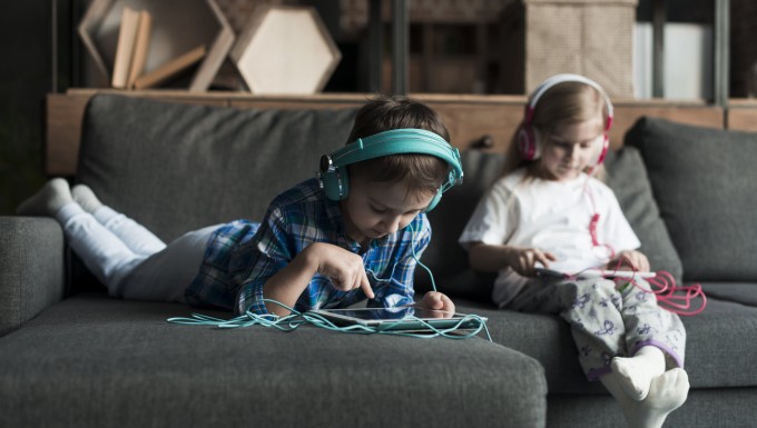 Ebookids - Photo créé par freepik -CC-BY-SA Deux enfants dans un canapé avec tablettes et casques audios