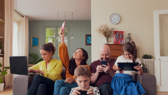 La famille tout écran. Tous droits réservés. Une famille rassemblée dans son salon. Chacun des membres utilisent un appareil numérique.