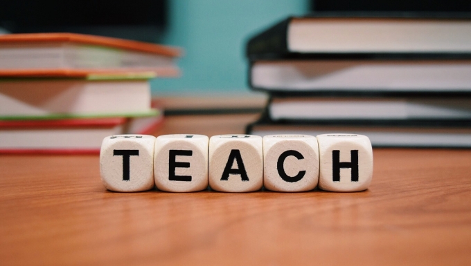 CC0 Public Domain : httpspixabay.comfrenseigner-l-%C3%A9ducation-l-%C3%A9cole-1968076 Dés marqués d'une lettre formant le mot "Teach" sur un bureau d'une salle de classe