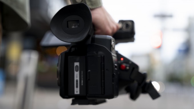 CC0 Freepik. Photo d'une caméra en gros plan tenue par un journaliste.