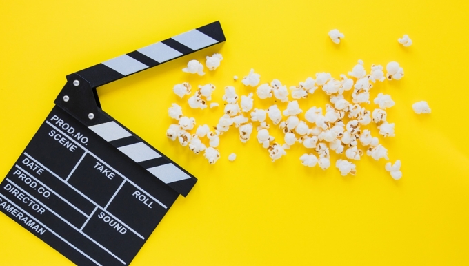 Un clap de cinéma et du popcorn sur fonds jaunes