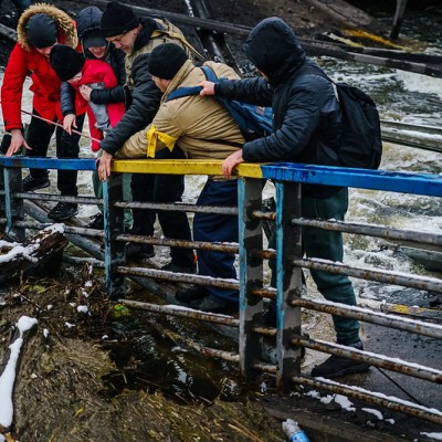 Des soldats ukrainiens aidant une famille à franchir un pont détruit à Irpin.
