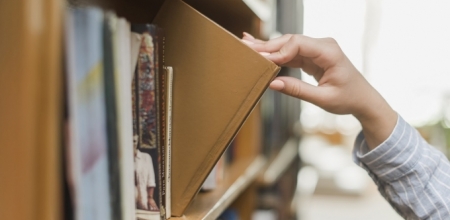 main prenant un livre sur une étagère