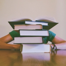 Un étudiant dormant sur son bureau dissimulé derrière une pile de livres.