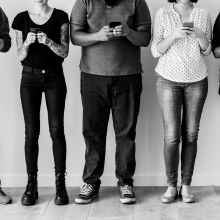 Photo en noir et blanc de personnes consultant leur téléphone portable.