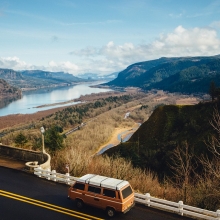 vue d'un paysage américian représentant les grands espaces. Un mini-van en premier plan représente le voyage. Au loin on voit un fleuve et de hautes montagnes